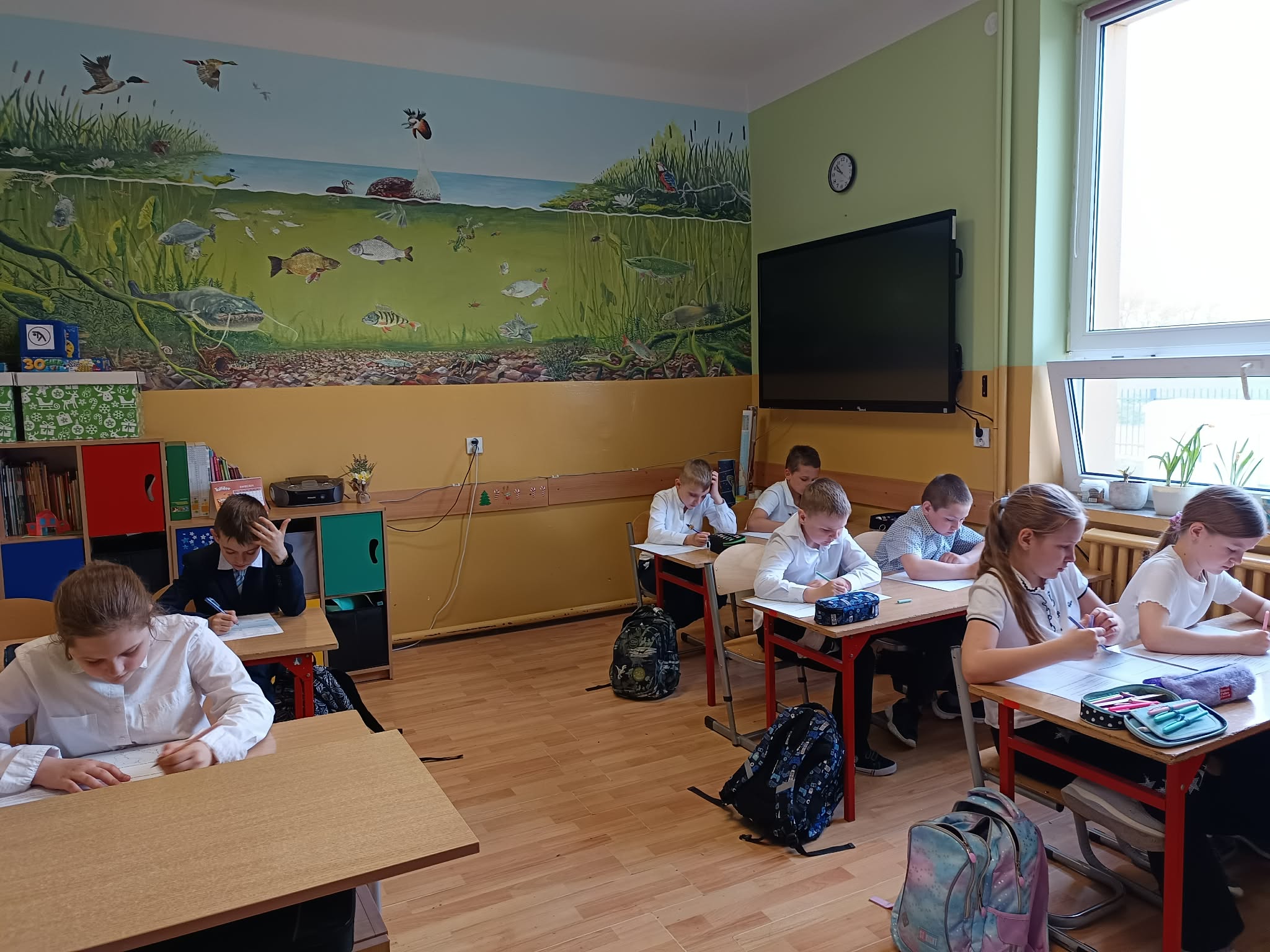 Widok całej klasy podczas sprawdzianu – uczniowie pracują samodzielnie przy swoich ławkach.